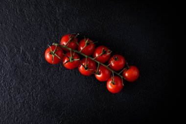 flatlay cherry tomatoes on a branch on a dark background