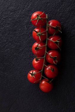 flatlay cherry tomatoes on a branch on a dark background