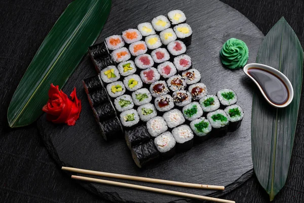 Bambuszlevelekkel Evőpálcikákkal Díszített Sötét Háttérre Fektetett Sushi Tekercsek — Stock Fotó