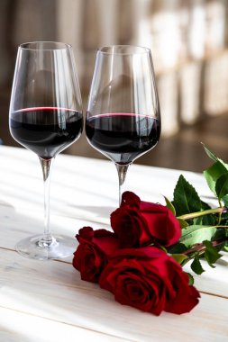 Romantik yemek. Güllü ve yapraklı iki kadeh şarap..