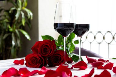 Romantik yemek. Güllü ve yapraklı iki kadeh şarap..