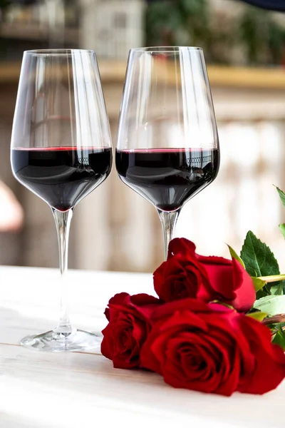 Romantik yemek. Güllü ve yapraklı iki kadeh şarap..
