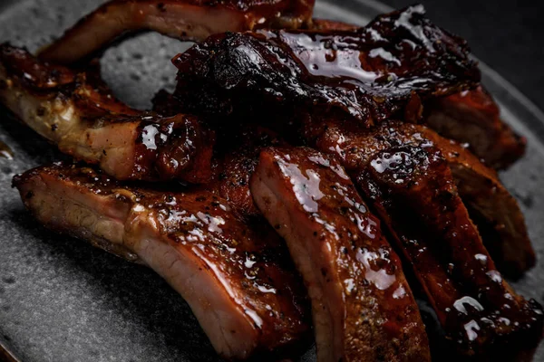 Smoked ribs in sauce on a plate on a dark background — Stock Photo, Image