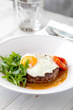 Kahvaltıda kızarmış yumurta, biftek, roka ve kurutulmuş domates.