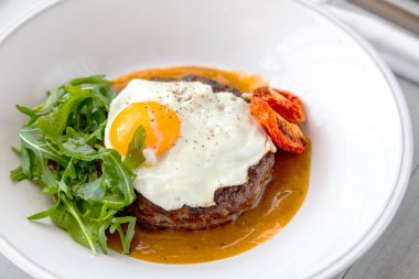 Kahvaltıda kızarmış yumurta, biftek, roka ve kurutulmuş domates.