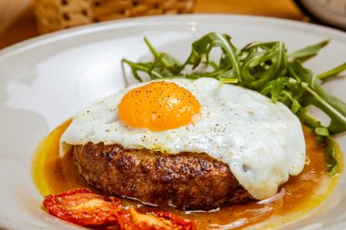 Kahvaltıda kızarmış yumurta, biftek, roka ve kurutulmuş domates.