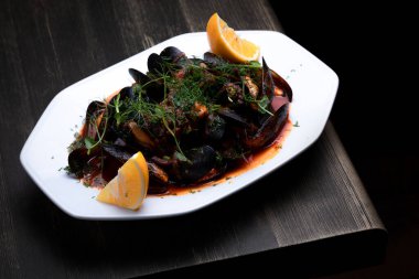 Domates soslu midye, mikroyeşillik ve limon, ahşap bir arka planda.