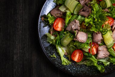 Taze sebze salatası ve koyu ahşap arka planda et.