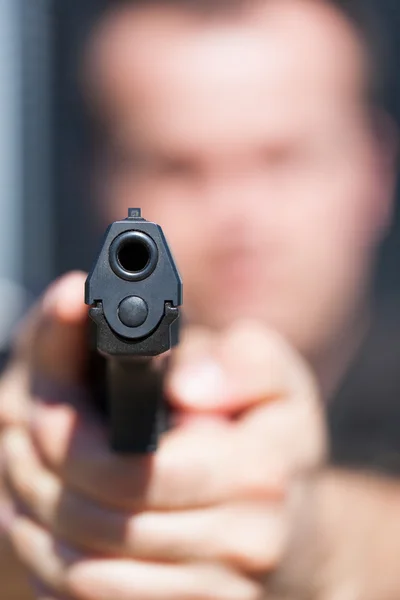 その男は銃から目指しています。銃のバレルに焦点を当てる. — ストック写真