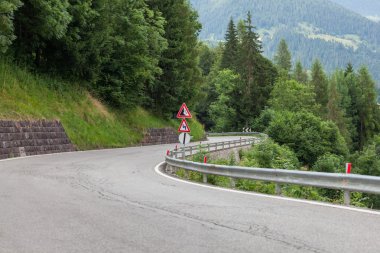 Uyarı trafik işaret dolambaçlı yol üzerinde metal kutup
