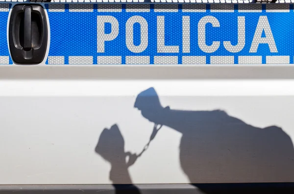 Sombra de um homem algemado a um carro da polícia . — Fotografia de Stock