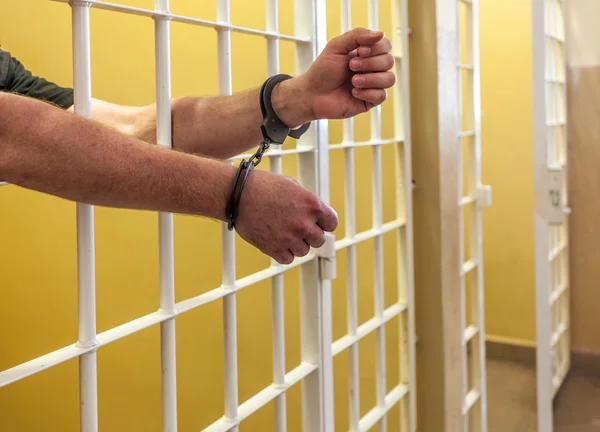 Prisoner in handcuffs locked in a cell. — Stock Photo, Image