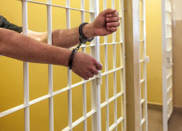 Prisionero esposado encerrado en una celda . Fotos De Stock