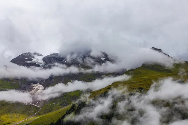 Ghiacciaio alpino e cime delle montagne tra le nuvole — Foto Stock