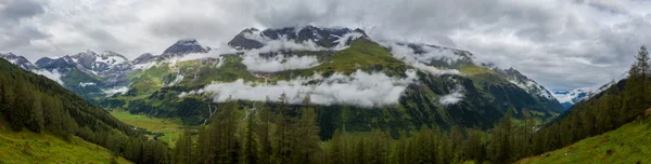 Alpine toppen van de bergen in de wolken - panorama — Stockfoto