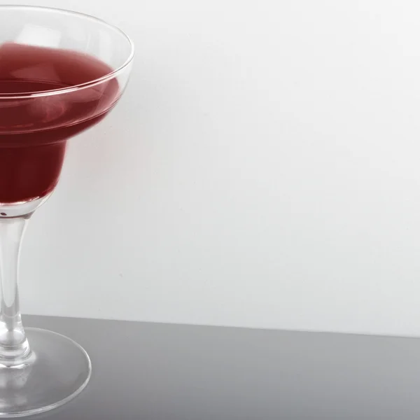 Glas med rød cocktail på grå baggrund - Stock-foto