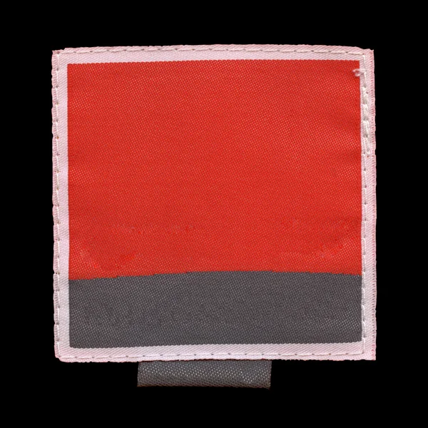 Červená černá textilní štítek izolované na černém pozadí — Stock fotografie