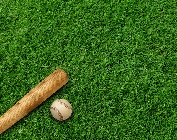 Baseball morcego e bola no fundo relvado verde — Fotografia de Stock