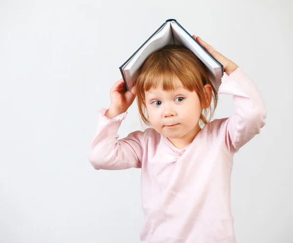 Χαριτωμένο κοριτσάκι που κρατάει το βιβλίο στο κεφάλι — 图库照片
