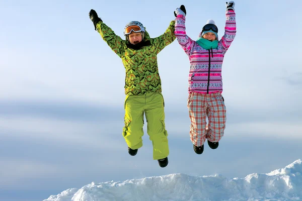 Snowboarders friends in bright vivid clothes jumping — Stock Photo, Image