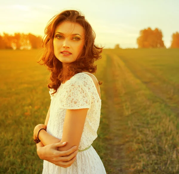 Mulher morena bonita no campo ao pôr do sol — Fotografia de Stock