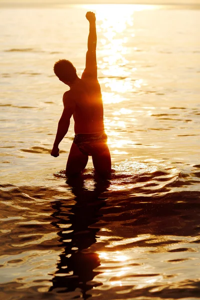 Hombre con la mano en alto en el amanecer en la playa — Foto de Stock