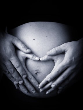 hamile kadın kalp şekli ile yapım karnının üzerinde eller
