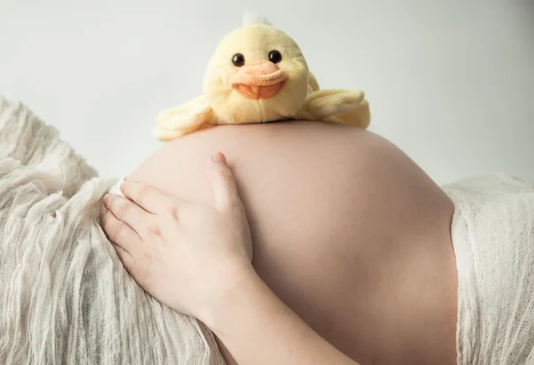 Pregnant belly lying with small duck — Stock Photo, Image