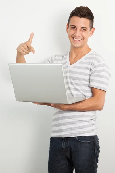 gülümseyen ve bir dizüstü bilgisayar işaret eden genç adam