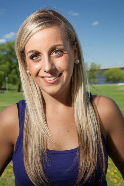 Porträt einer jungen blonden Frau, die draußen lächelt lizenzfreie Stockbilder