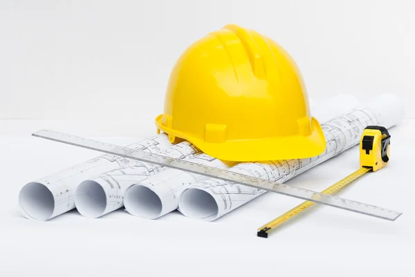 Rolls of architectural drawings and yellow helmet — Stock Photo, Image