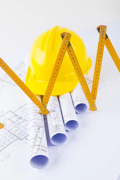 Yellow helmet with level and project drawings — Stock Photo, Image