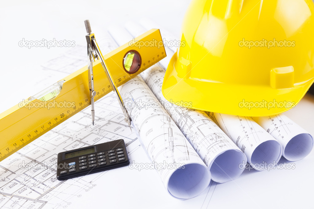 Yellow helmet and heap of project drawings and construction tools