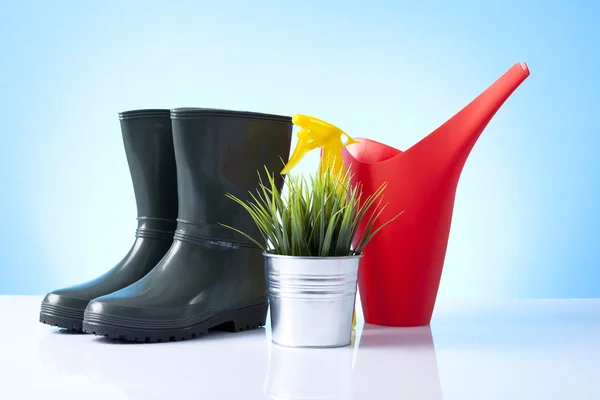 Watering can and garden boots on blue background — Stock Photo, Image