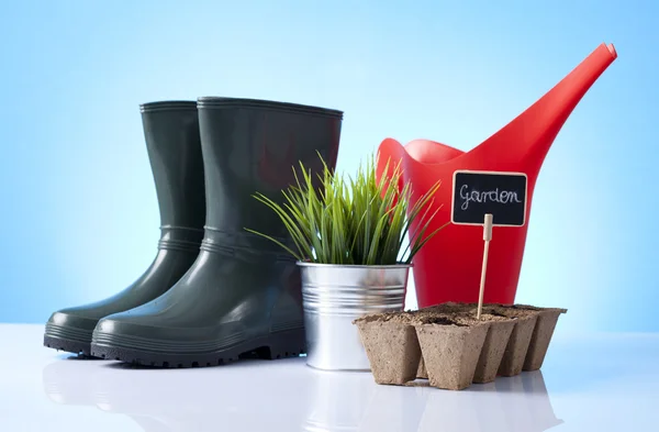 Arrosoir et bottes de jardin sur fond bleu — Photo