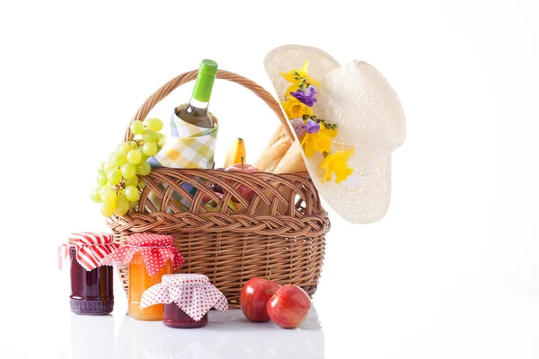 Picnic basket with bottle of wine,fruits, bread and summer hat isolated on white