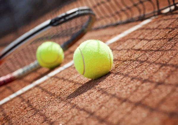 关闭的网球球拍和球在红土网球场 — 图库照片