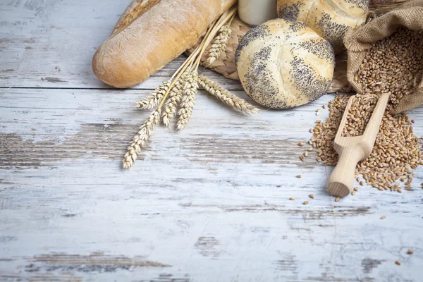 Rustic bread and wheat on an old vintage planked wood table. background with free text space — Stock Photo, Image