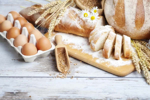 Roti dan gandum berkarat di meja kayu yang sudah tua. latar belakang dengan ruang teks bebas — Stok Foto