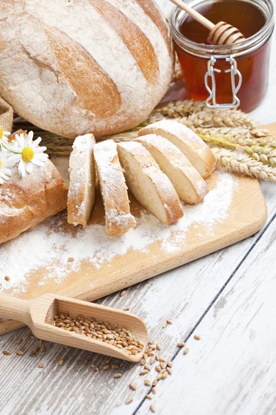 Rustic bread and wheat on an old vintage planked wood table. background with free text space — Stock Photo, Image