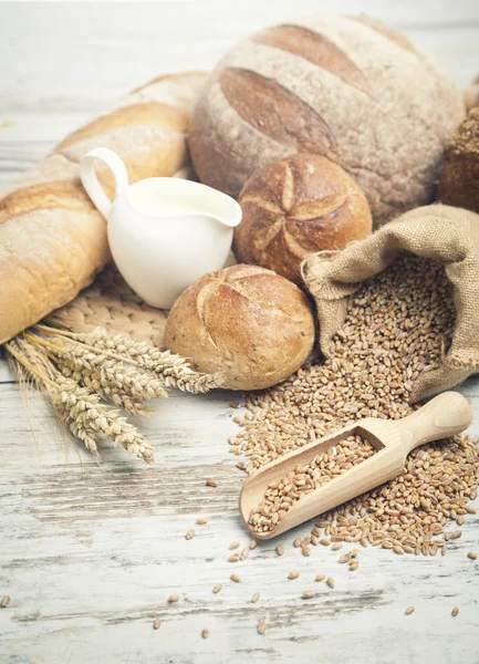 Rustikales Brot und Weizen auf einem alten Holztisch. Hintergrund mit freiem Textplatz — Stockfoto