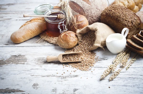 Rustikales Brot und Weizen auf einem alten Holztisch. Hintergrund mit freiem Textplatz — Stockfoto