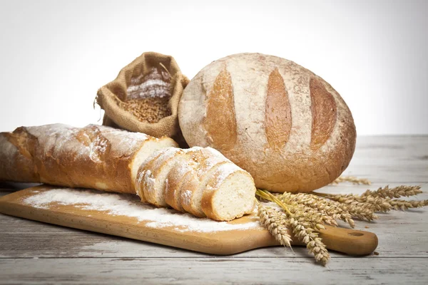 Pane rustico e grano su un vecchio tavolo di legno fasciato d'epoca. sfondo con spazio di testo libero — Foto Stock