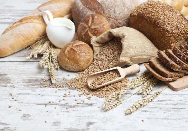 Roti dan gandum berkarat di meja kayu yang sudah tua. latar belakang dengan ruang teks bebas — Stok Foto