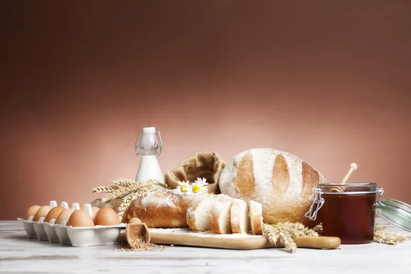 Pâine franceză proaspăt coaptă cu țesătură de homespun și vârfuri de grâu pe fundal alb . — Fotografie, imagine de stoc