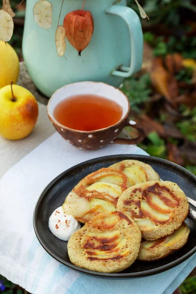 Whole wheat apple pancakes served with tea in the garden. Rustic style. — Stock Photo, Image
