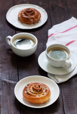 Kahveyle servis edilen kremalı tarçınlı çörekler. Kırsal biçim.