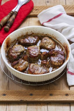 Soğan sosunda pişirilmiş fileto ve ahşap bir masada otlar. Kırsal biçim, seçici odak.