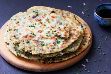 Homemade appetizing scallion pancakes served with soy sauce. Selective focus.