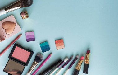 Mavi arka planda farklı ruj tonlarının makyaj ve kozmetik araçları.